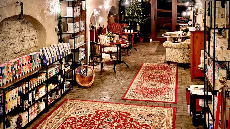 Tea store and salon, © August Lechner Cozy room with red carpets, shelves full of products and seating in the tea room.