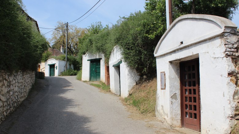 Wine cellar lane Heakrotza, © Weinviertel Tourismus A narrow street in a wine cellar lane with white wine cellars and green doors in Herrnbaumgarten.