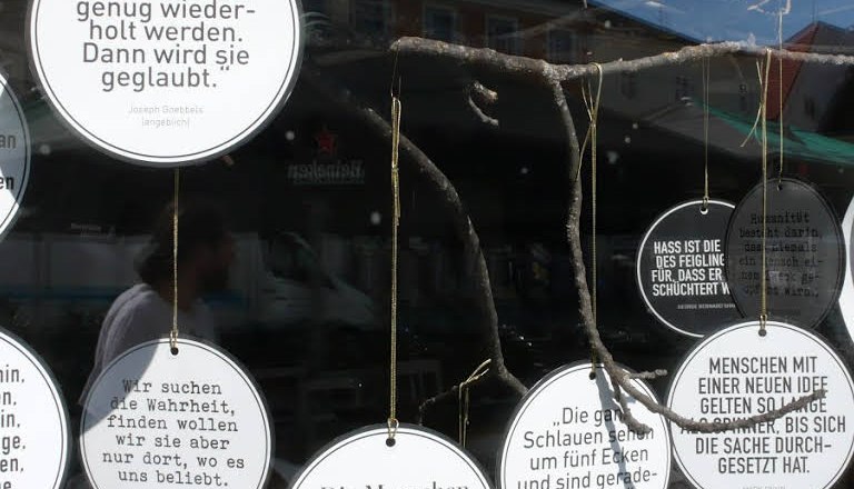 Leitmotifs, © Süd - das Kulturcafé Round signs with quotes hang in a shop window.