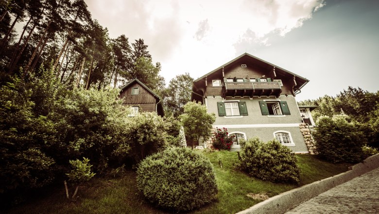 Villa Antoinette, © Matthias Kronfuss A villa with a green garden and trees in the background.