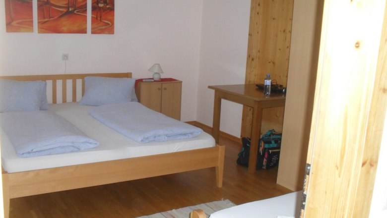 Room view in the house Horak, © Hubert Horak A simply furnished bedroom with a double bed, wooden furniture and a painting on the wall.