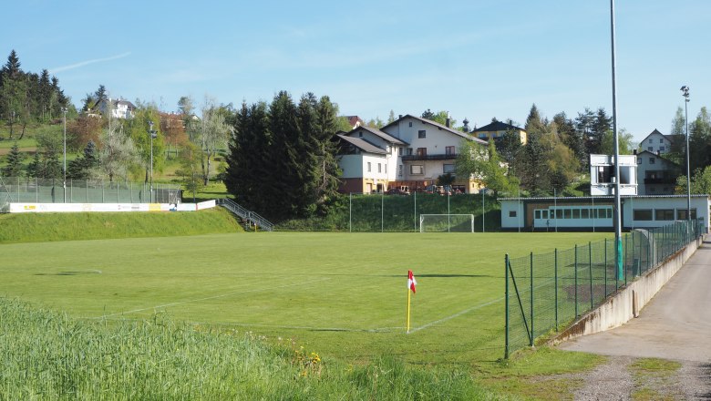 Soccer pitch and tennis courts, © MG Sallingberg An empty soccer pitch with surrounding buildings and trees on a sunny day.