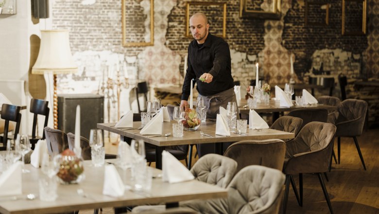 Differently designed feel-good rooms, © Niederösterreich Werbung/Michael Reidinger Waiter sets a stylish table in an elegant restaurant.