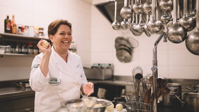 Inn cuisine with Waldviertel carp topping, © Niederösterreich Werbung/Mara Hohla A smiling chef in a professional kitchen holding a ball of dough.