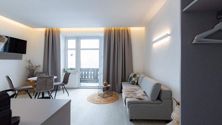 Apartment 4, © Atelier Fürtner-Ton Modern living room with gray sofa, dining table and balcony.