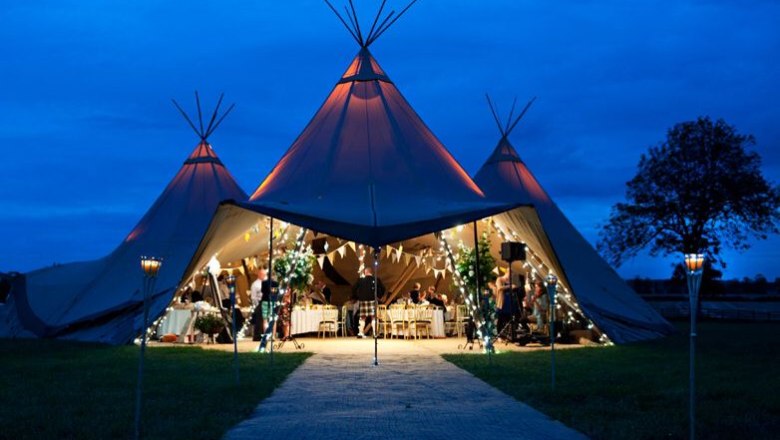Connected tipi, © Szilagyi An illuminated tipi tent at night with festive decorations and guests inside.
