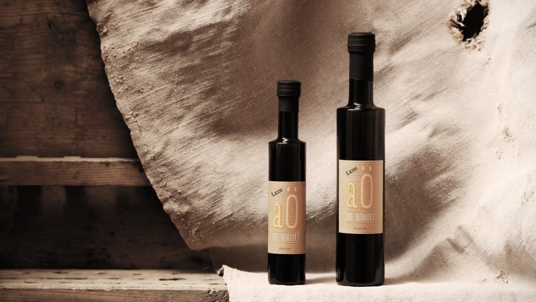 Gilli Mill Packshot, © K. Vyhnalek Two bottles of linseed oil in front of a rustic background.