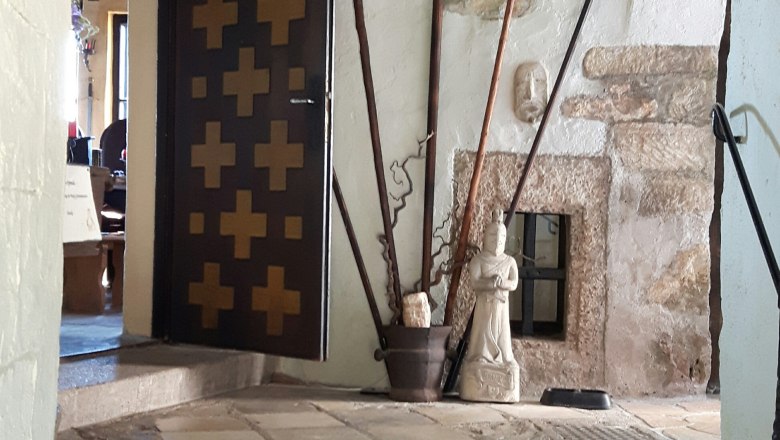 In the castle, © www.burg-grimmenstein.at Interior view of a castle with weapons, a boar's head and a statue.