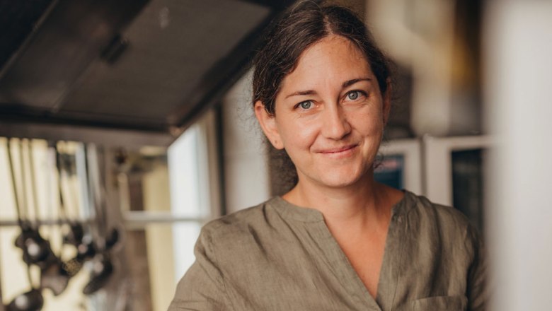 Home-style cooking by Bernadette Fellner, © Niederösterreich Werbung/Daniela Führer A woman in a kitchen, smiling, with brown hair and a green shirt.