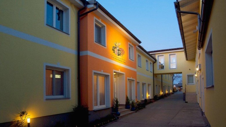 Hotel Radlinger, © Hotel Radlinger Exterior view of the Hotel Radlinger at dusk with yellow and orange facades.