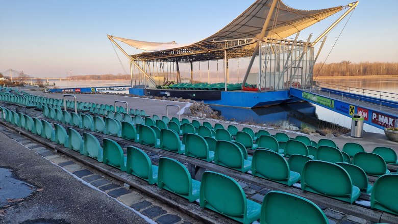 Danube stage in winter, © Donau Niederösterreich, K.Kancer Open-air stage with green rows of seats on a riverbank.