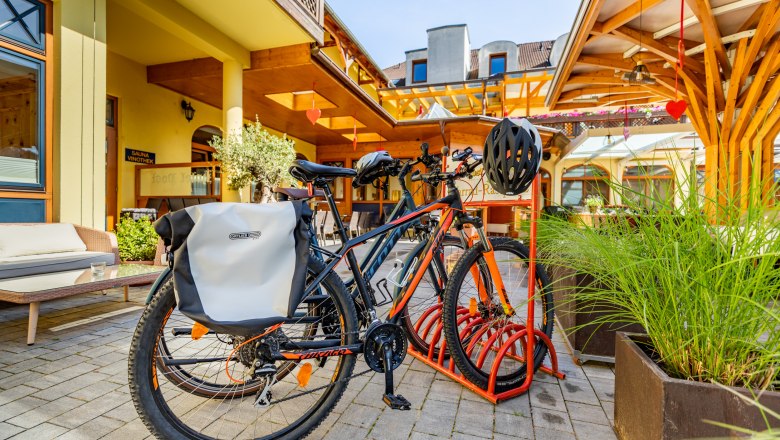 Bicycle parking lot at the Hotel Post-Hönigwirt, © Wiener Alpen/Martin Fülöp Bicycles on a bicycle stand in front of a hotel building.