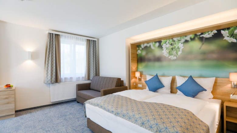 R&R Residences, hotel rooms, © Doris Schwarz-König Modern hotel room with double bed, sofa and large mural with floral motif.