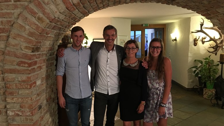 Böhm family, © Gasthof Böhm Four people stand smiling under a brick arch in a room with hunting trophies on the wall.