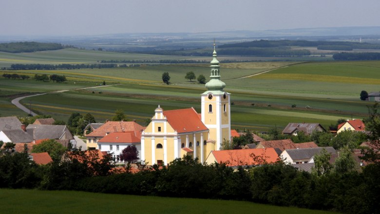 Ottenthal, © Gemeinde Ottenthal View of a church in Ottenthal with surrounding houses and wide fields in the background.