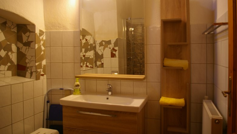 Bathroom, © Fam. Zangl Bathroom with mirror, washbasin, tiles and shelf with towels.