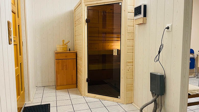 sauna, © Angelika Burger Interior view of a sauna room with wooden walls, a glass door and a small wooden cabinet.