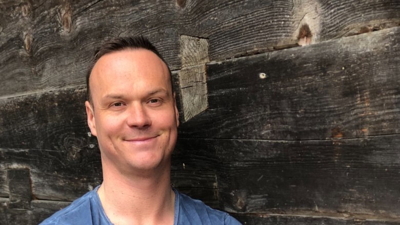 Herwald Hauleitner, © Hauleitner Man in blue T-shirt in front of wooden wall.