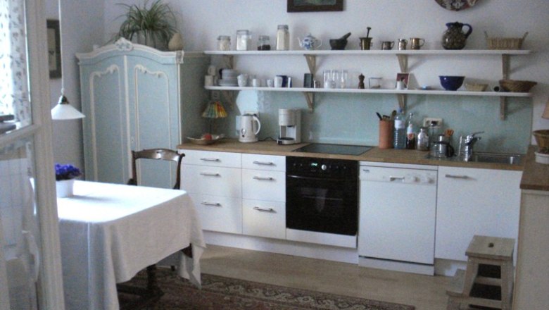 Kitchen, © C. Wardell Cozy kitchen with dining table, cupboards and shelves.
