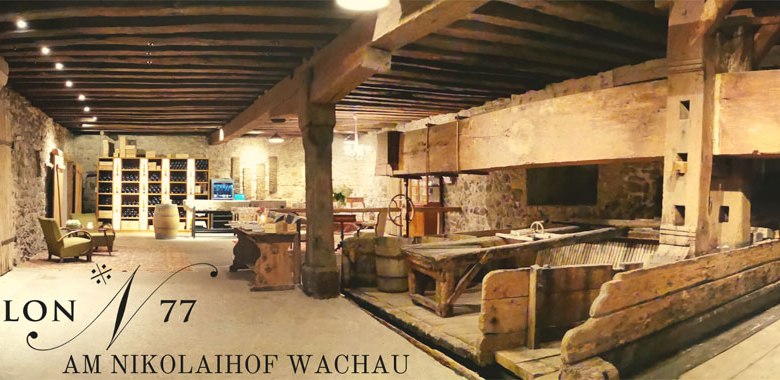 Salon 77, © Marlene Bergkirchner Interior view of a rustic wine cellar with wooden beams and stone walls, labeled 'Salon 77 am Nikolaihof Wachau'.