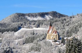 St. Wolfgang's Church, © Marktgemeinde Kirchberg a.W./Wolfgang Riegler Winter landscape with a church in front of a wooded hill.