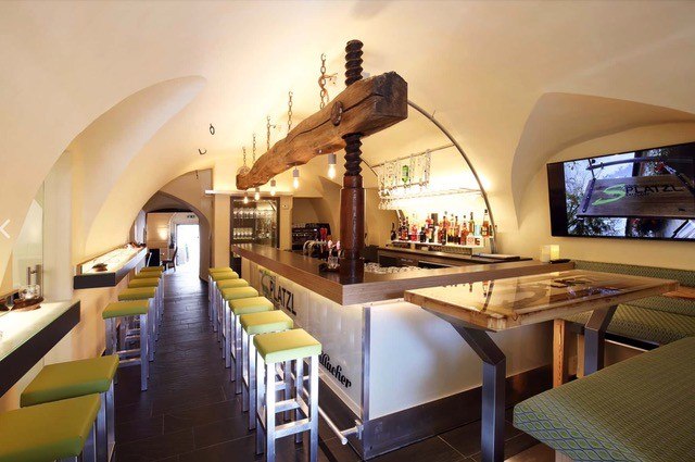 S Platzl Restaurant, © Schilowsky_NM_©redtenbacher Interior view of a modern restaurant with bar, green stools and vaulted ceiling.
