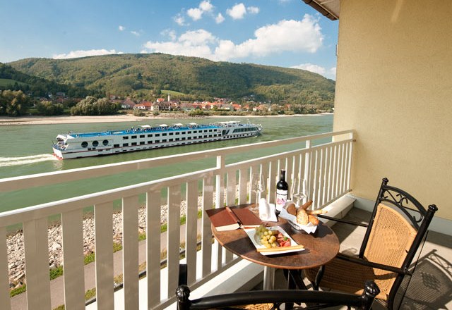 View Suite, © Residenz Wachau Balcony with table, wine and snacks, view of the river and passing ship.