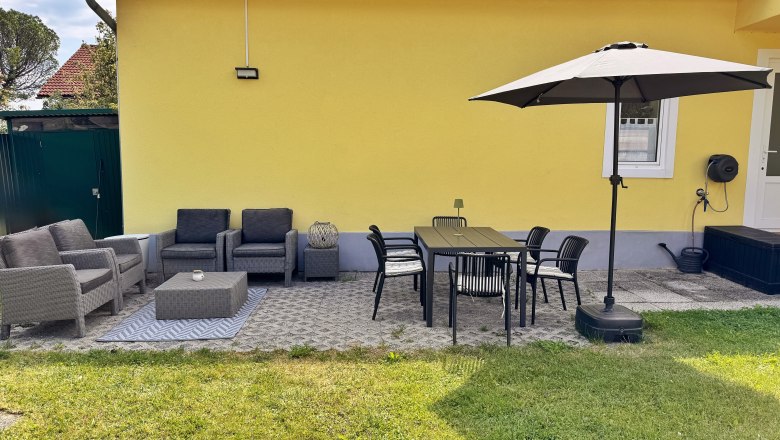 Terrace, © Christoph Menhofer Terrace with yellow house wall, gray seating furniture, dining table, chairs and parasol.