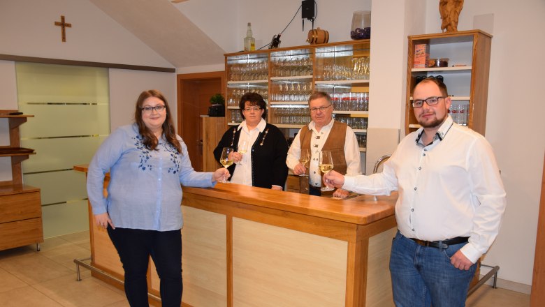 Piller family, © Familie Piller Four people are standing at a bar holding glasses of wine.