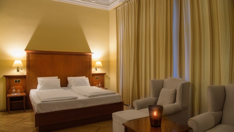 Double room, © Traumbild - Gerhard Wolkersdorfer Elegant double room with a large bed, two armchairs and a table with a candle.