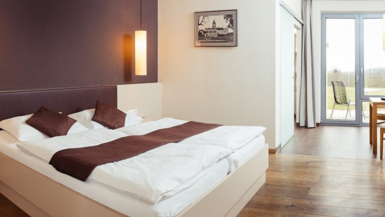 Quiet rooms with great comfort., © Weingut & Weinblick Grafinger Modernly furnished hotel room with double bed, wooden floor and access to a balcony with a view.