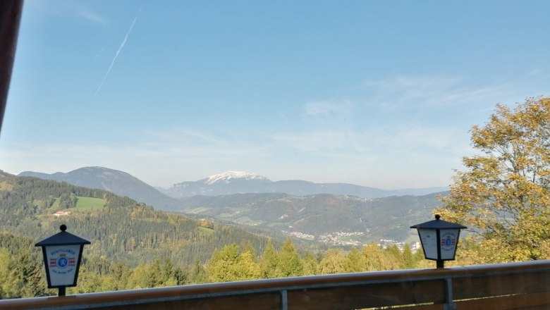 View from the restaurant, © Wiener Alpen View from a restaurant balcony of a mountainous landscape with forest and a snow-covered peak in the background.