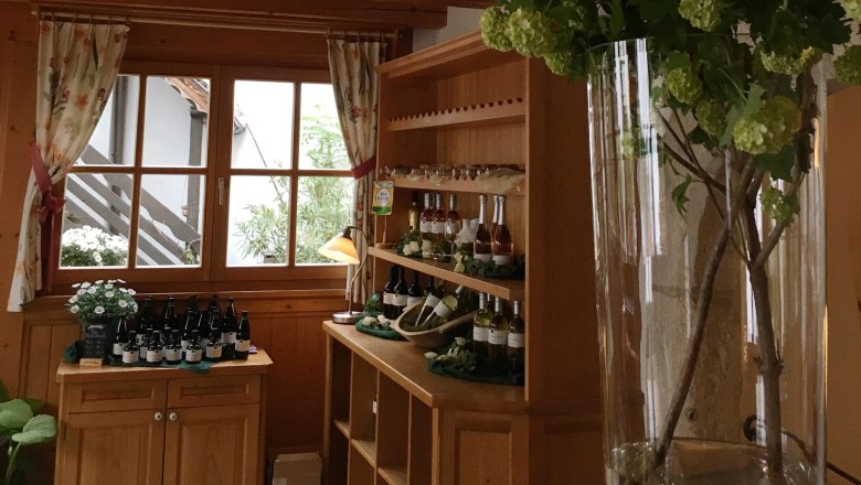 Organic winery & wine tavern Hofschneider, © Bio Weingut Hofschneider Interior view of a winery with wooden furniture and wine bottles.