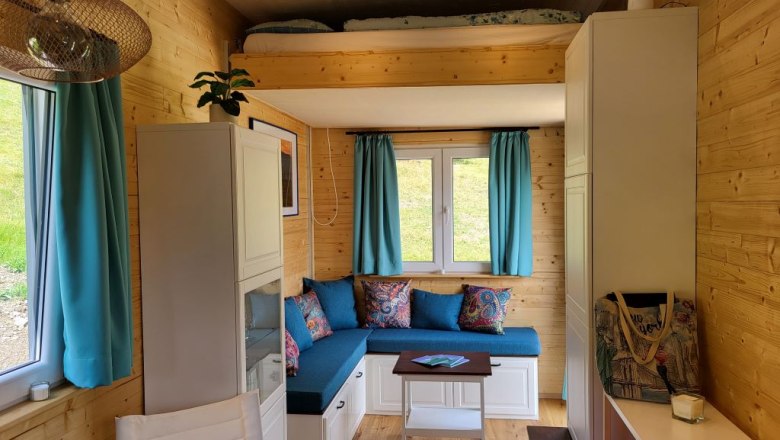 Living area with fold-down bed, © Villa to go Small living area with fold-down bed, blue curtains and wooden walls.