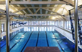 Regionalbad Gänserndorf, © Martin Schiffer Interior view of a modern indoor pool with swimming lanes and climbing wall.