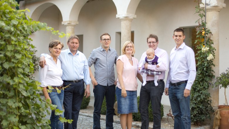 Müllner family, © Astrid Bartl A family stands outside in front of a building with arches, surrounded by plants.