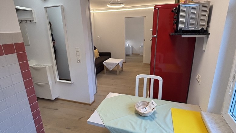 TDR House Morning Sun Living Room, © Fam Pauker Small living room with dining table, chairs, red fridge and sofa.
