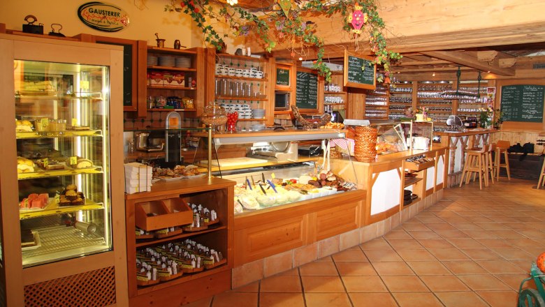 Gausterer, © Gausterer Markus Interior view of a cozy café with counter and displays.