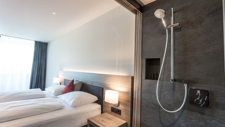 Double bed in a modern double room, © KASTNER NEW MEDIA - kastner.tv Modern hotel room with double bed and open shower.