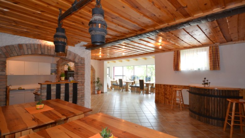 Stüberl - Winzerhof Stauffer, © Winzerhof Stauffer Interior view of a rustic dining room with wooden tables and ceilings, bar area and large windows.