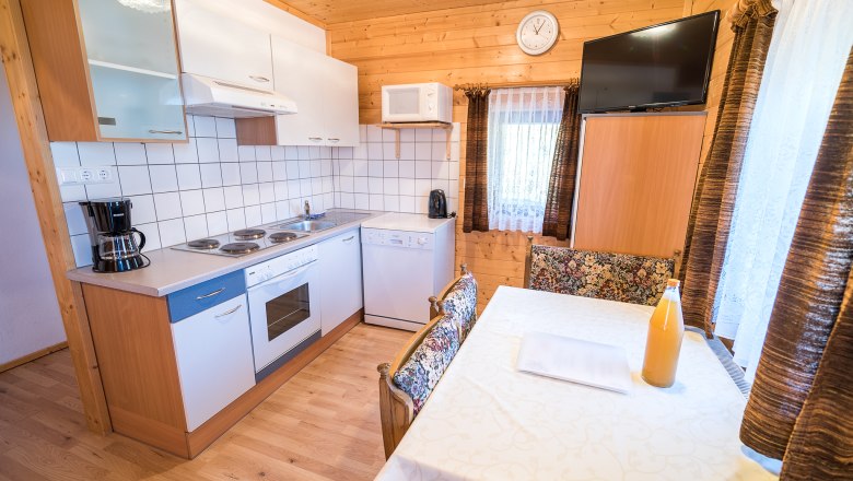 Apartment "Panorama" Kitchen, © Familie Morgenbesser Cozy kitchen with wooden walls, dining table, stove, coffee maker and TV.