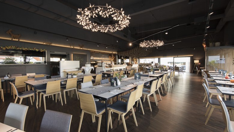 Modern restaurant area, © Weinlodge Siedler Modern restaurant with wooden chairs and decorative chandeliers.