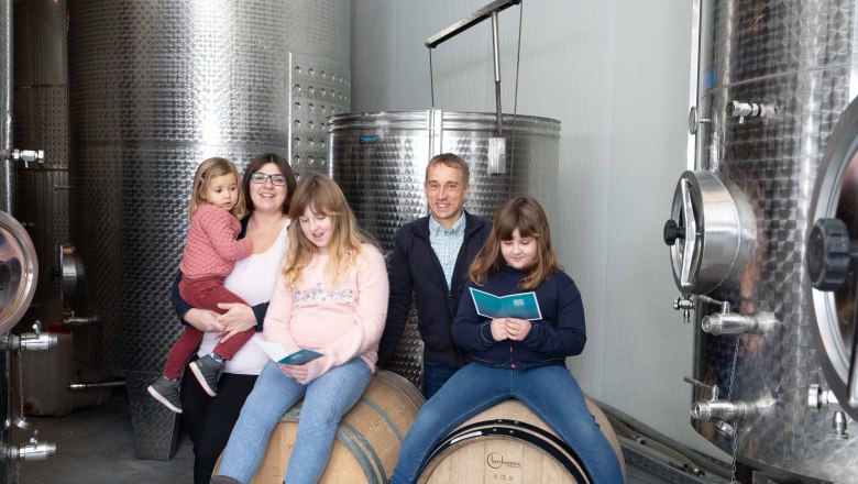 Berger family, © Richard Stöger A family poses in front of large stainless steel tanks in a winery.