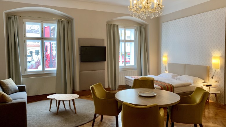 Residence 2, © Daniela Matejschek Elegant room with bed, sofa, table and chandelier.