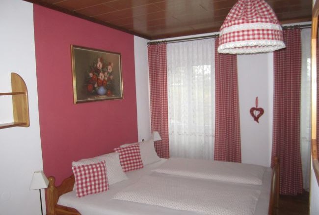 Hansy House, © Fam. Schrammel Bedroom with red and white checked curtains and bed linen.