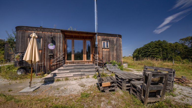 SONNENTOR country lofts, © Niederösterreich Werbung / Maximilian Pawlikowsky Wooden house with terrace and pallet furniture in a rural setting.