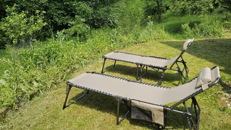 Orlet on the Rax, © Sofia Orlet Two sun loungers on a meadow with a view of wooded mountains under a blue sky.