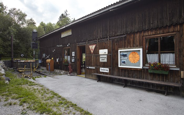 Rack railway exhibition, © Wiener Alpen, Foto: Bene Croy Wooden building with signs and flowers, part of an exhibition.