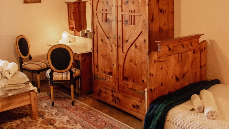 Orlet on the Rax, © Sofia Orlet A cozy room with wooden furniture, a carpet and a bed with folded towels.