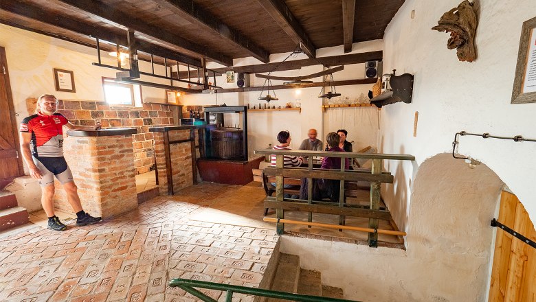 Cellar wellness area Jetzelsdorf, © Initiative Pulkautal / Mödl Cozy wine cellar with people at a table and a man in cycling clothes.